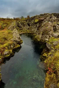 Thingvellir Prints: Clear spring surrounded by mossy lava rocks at Thingvellir National Park in Iceland reflecting the rugged landscape