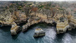 Geological Prints: Cliffs near coastline during sunset with water surrounding rocky formations in Algarve region
