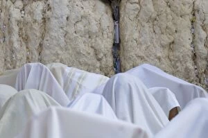 Close up of men covered with white prayer shawls receiving