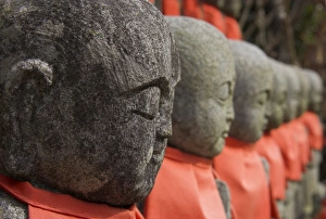 Shinto Prints: Close up of a row of stone figures wearing red cloth