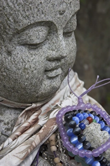 Bracelet Prints: Close up of a traditional stone figure with prayer bracelets