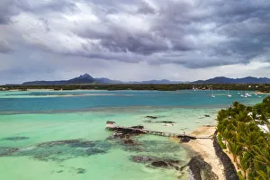 Clouds over lagoon and pier by a palm fringed beach, aerial view, Trou d Eau Douce