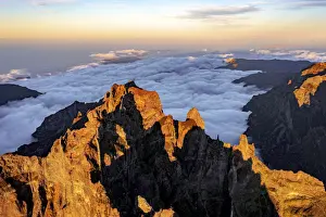 Solar Flare Prints: Clouds surrounding the rocky peak of Pico das Torres lit by sunset, Madeira island