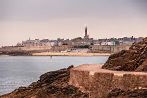Ramparts Prints: Coastal view of Saint-Malo city with stone walls and spire seen from Dinard walkway along the Brittany shore in France