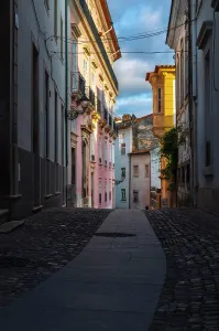 Cobblestone Prints: Coimbra street scene during sunset with colorful buildings and cobblestone pathway in Central Portugal
