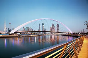 Aesthetic Prints: Colorful sunset over Dubai Downtown skyscrapers and newly built Tolerance bridge viewed from Dubai water canal