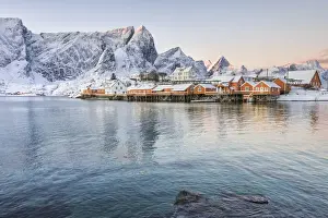 The colors of dawn frame the fishermens houses surrounded by snowy peaks, Sakrisoy