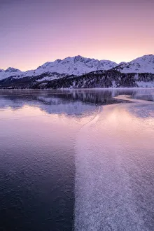 Engadine Prints: Colors of sunrise is reflected on the icy surface of Lake Sils, Engadine Valley