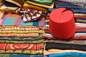 Images Dated 11th April 2009: Colourful cotton fabric and a traditional fez for sale in a shop in Luxor, Egypt, North Africa