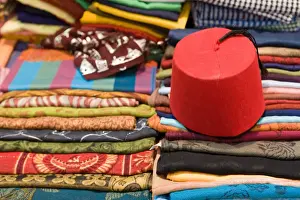 Fabric Prints: Colourful cotton fabric and a traditional fez for sale in a shop in Luxor