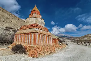 Colourfully painted Buddhist stupa in front of mountain landscape, eroded landscape and houses of Garphu behind, Garphu, Kingdom of Mustang, Himalayas, Nepal, Asia