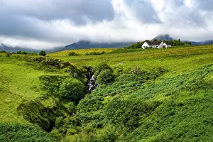 Sheep Prints: Cottage and waterfall stand in green landscape near Staffin on the Isle of Skye in Scotland surrounded by hills