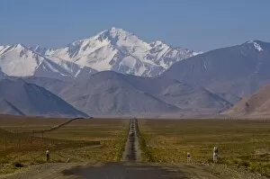 Country road leading to snow covered mountains, Karakul, Tajikistan, Central Asia