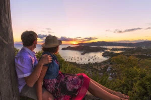 35 39 Years Gallery: Couple look to the English Harbor from Shirley Heights at sunset, Antigua, Antigua and Barbuda