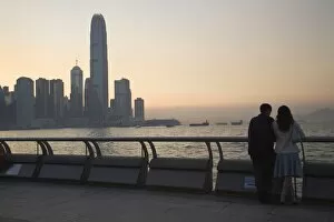 Couple looking at Victoria Bay and city skyline at sunset, Hong Kong, China, Asia