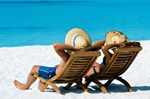 Adults Prints: Couple lying in deck chairs on beach, The Maldives, Indian Ocean, Asia