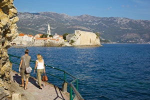 Couple walking along coast towards Old Town, Budva, Montenegro, Europe