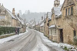 Hedge Prints: A couple walking up the hill in Castle Combe with an umbrella protecting them