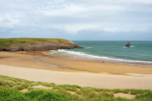 United Prints: Couple walks with dog past Church Rock on Broad Haven South beach in Pembrokeshire
