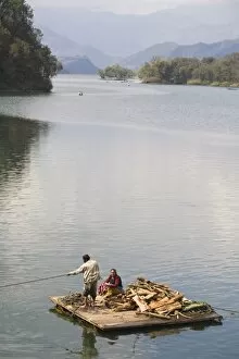 Couple on wooden raft with firewood, Fewa (Phewa) Lake, Pokhara, Nepal, Asia