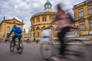 Theatres Prints: Cyclists passing the Sheldonian Theatre, Oxford, Oxfordshire, England, United Kingdom
