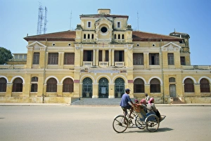 Trishaws Prints: A cyclo passing the Old Post Office in Phnom Penh in Cambodia, Indochina