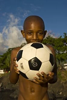 A dark skinned boy smiling and holding a football, Moroni, Grand Comore, Comores, Africa