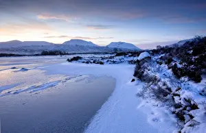 Dawn view of frozen Loch Ba on snow-covered Rannoch Moor, Highland, Scotland