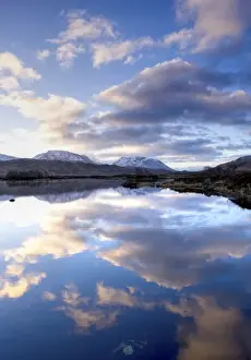 Dawn view of Loch Ba reflecting the sky and distant snow-capped mountains