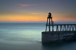 Daybreak over Whitby East Pier and lighthouse, North Yorkshire, England, United Kingdom