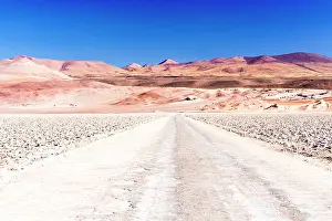 Vast Prints: Empty desert road towards red rocky mountains, Salar de Arizaro salt flat, Puna, Argentina