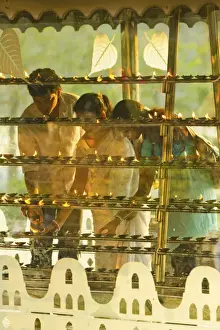 Devotees lighting candles at sunset in the Temple of the Sacred Tooth Relic