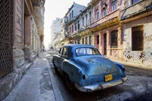 Dilapidated American car parked on a street of ornate colonial buildings