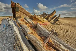 Metal Prints: Disintegrating wreck rests on the beach at Crow Point in Devon near Barnstaple under a cloudy sky