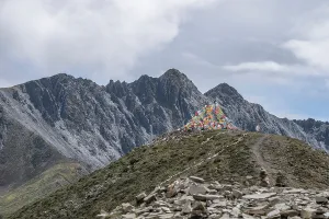 Peaks Prints: Dramatic clouds surround Zimei mountain pass with prayer flags and rugged peaks in Sichuan