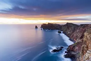 Dramatic sky at dawn on cliffs washed by ocean from Ponta Do Rosto viewpoint