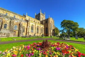 United Prints: Dunfermline Abbey stands tall with colorful flowers in front during sunny weather in Dunfermline