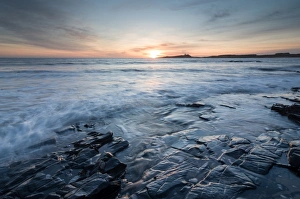 Dunstanburgh Castle at sunrise, seen from Embleton Bay, Northumberland, England, United Kingdom