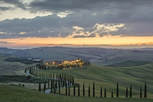 Dusk on green hills surrounded by cypresses and farm houses, Crete Senesi (Senese Clays)