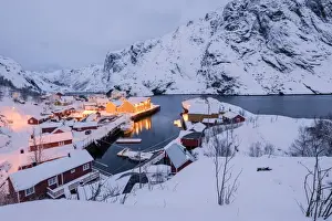 Dusk lights on the fishing village surrounded by snowy peaks, Nusfjord, Nordland
