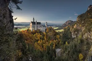Fussen Prints: Dusk lights on Neuschwanstein Castle surrounded by colorful woods in autumn, Fussen