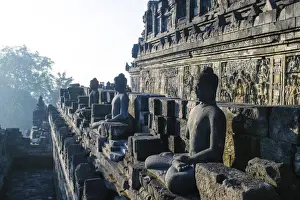 Borobodur Prints: Early morning light shining on Buddhas sitting in the temple complex of Borobodur