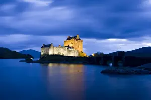 Eilean Donan Castle floodlit against the deep blue twilight sky and water of Loch Duich