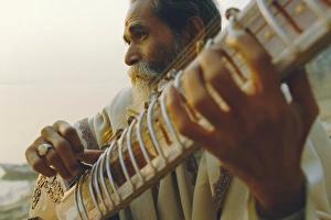 Elderly man playing the sitar beside the Ganges (Ganga) River