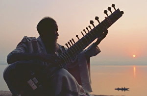 Elderly man playing the sitar beside the Ganges (Ganga) River
