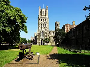 Viewing Prints: Ely Cathedral stands tall on a clear day with historical cannon in the foreground at Ely Cambridgeshire