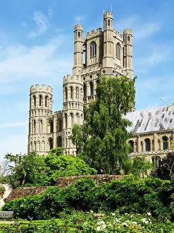 Cambridgeshire Prints: Ely Cathedral stands tall in Ely Cambridgeshire with clear blue skies above and greenery surrounding its base