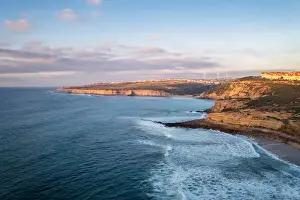 Drone Shot Prints: Ericeira drone aerial view on the coast of Portugal with surfers on the sea at sunset