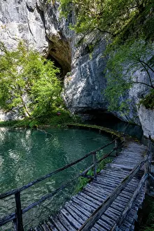 Trail Prints: Explore the beauty of Plitvice Lakes National Park in Croatia with lush nature and clear waters near a cave entrance