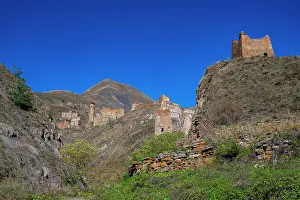 Stones Prints: Exploring an abandoned mountain village in Chechnya surrounded by steep hills under a clear blue sky